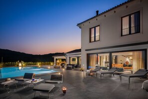 Een modern huis met een zwembad, terras en uitzicht op de bergen.