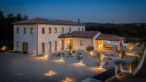 Ein zweistöckiges Haus mit Pool, umgeben von einem beleuchteten Garten.
