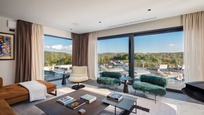 Ein modernes Wohnzimmer mit großem Fenster, das einen Pool und eine Außenbereichs-Sitzgruppe zeigt.
