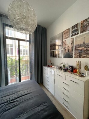 Ein Schlafzimmer mit Bett, Kommode, einer Lüster und Stadtansichten an der Wand.