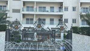 Una fuente con chorros de agua frente a un edificio con balcones y una pared de azulejos.