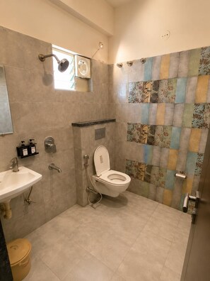 A bathroom with a toilet, sink, shower, and tiled walls. - Kubo By Convivial Hotels (Indore)