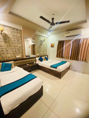 A hotel room with two beds, a ceiling fan, an air conditioning unit, and a large mirror on the wall. - Kubo By Convivial Hotels (Indore)