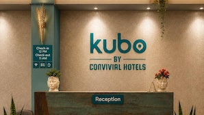 Una recepción con un cartel que dice 'kubo by Convival Hotels', horarios de entrada y salida, y una etiqueta de recepción.