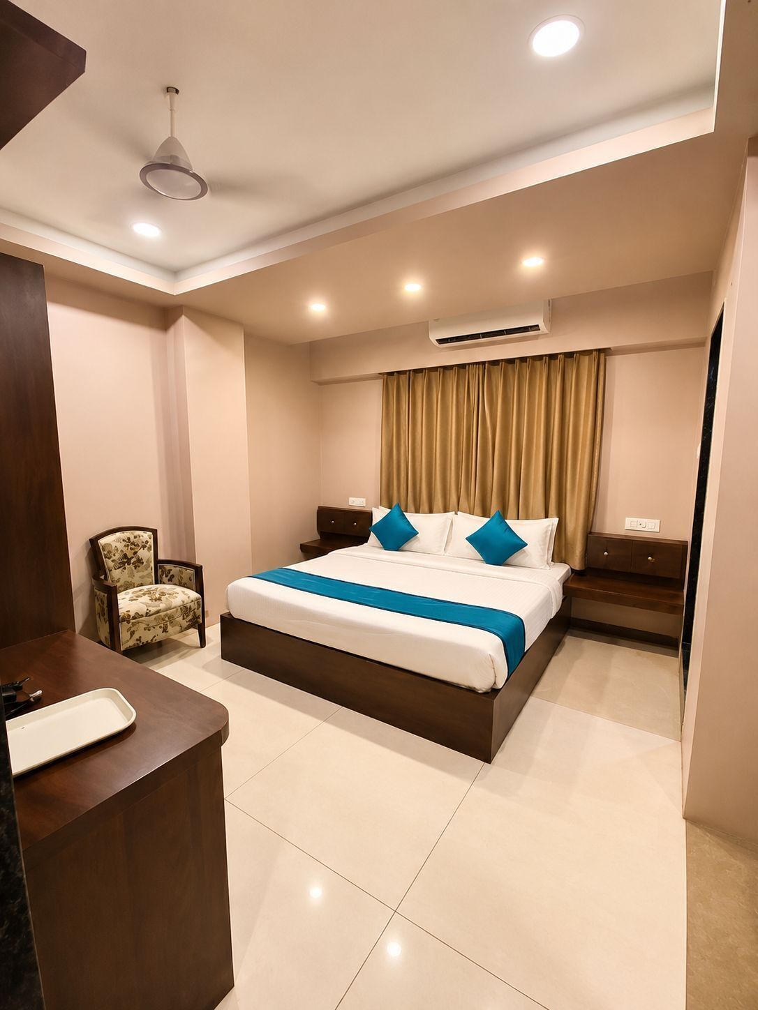 A hotel room with a bed, bedside tables, a chair, a desk, and an air conditioning unit.