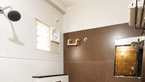 Un baño con inodoro, ducha, lavamanos y espejo.