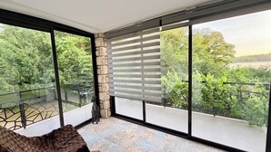 A balcony with a view of trees and a distant landscape, a stone wall, and a cushioned seating area.