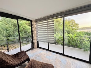 A balcony with a view of trees and a distant landscape, a stone wall, and a cushioned seating area.