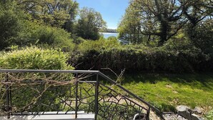A metal staircase leading to a viewing platform overlooking a lake, surrounded by dense greenery and trees.