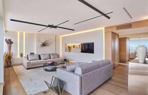 Ein modernes Wohnzimmer mit einer Couch, einem Couchtisch und einem an der Wand befestigten Flachbildfernseher.