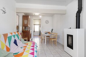 A room with a bed, a dining table, chairs, a cabinet, and a white wall with a clock.