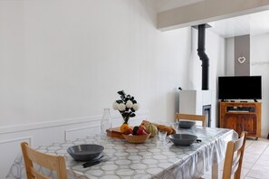 A dining area with a table set for four, a television, and a wooden cabinet.