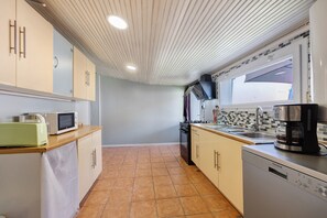 A compact kitchen with a microwave, toaster, stove, sink, and dishwasher.