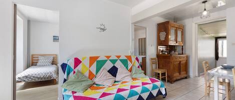 Una habitación con un sofá de patrón geométrico y colores vivos, un mueble de madera y una mesa de comedor con sillas.