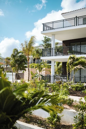 A multi-story hotel with balconies, surrounded by lush greenery and palm trees. - The Breeze -Blue Bay Golf & Beach Resort (Sint Michiel)