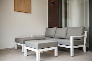 A modern living room with a sectional sofa, a matching ottoman, and a wall-mounted light fixture.