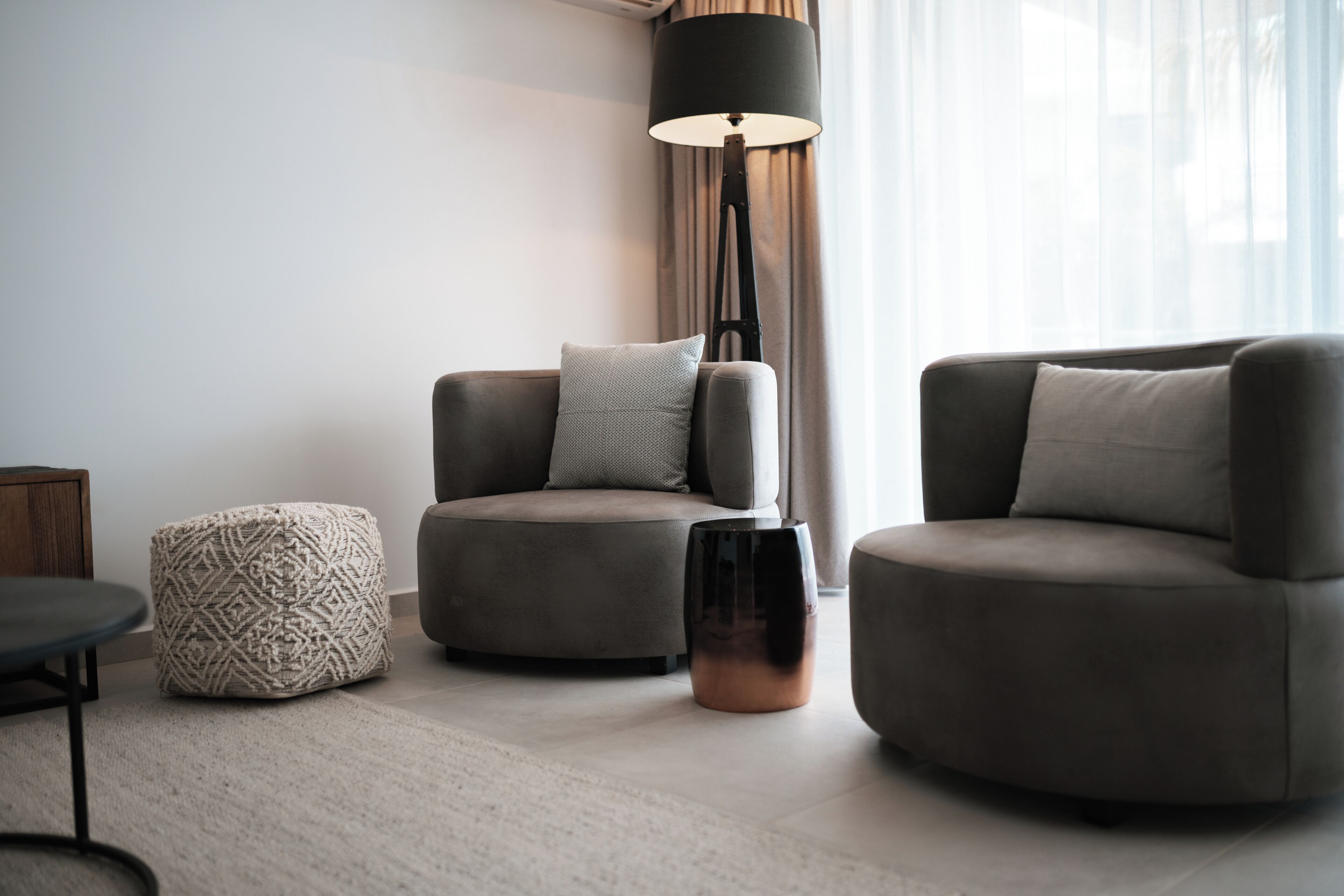 En moderne stue med sofa, skammel og gulvlampe.