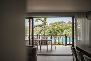 A room with a view of a pool and palm trees.