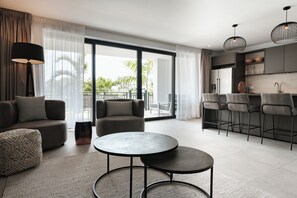 Un salon moderne avec un canapé, deux tables rondes et un coin cuisine équipé de tabourets de bar.