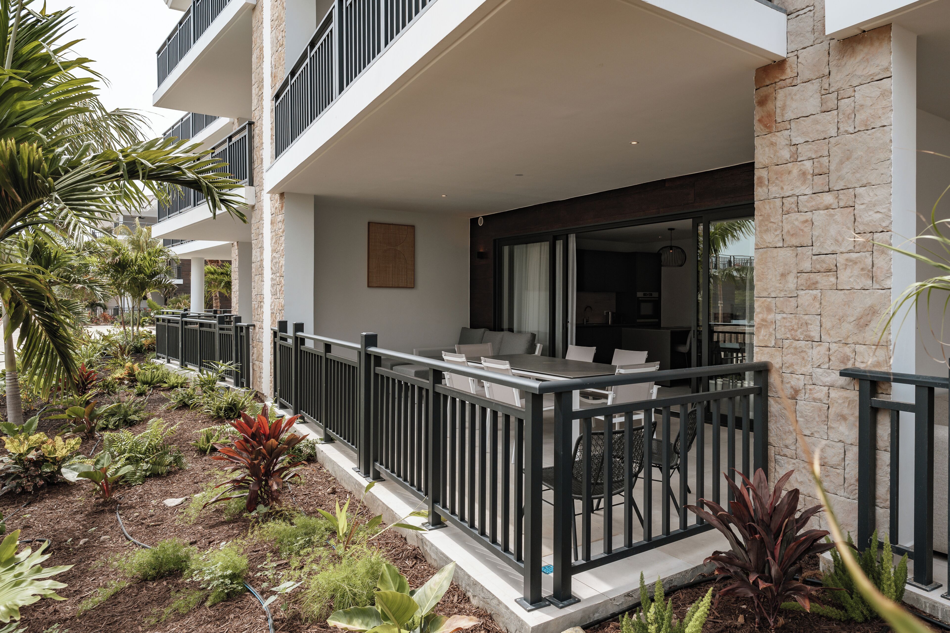 A modern building with a balcony, outdoor seating, and a garden area.