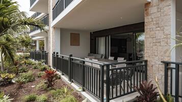 A modern building with a balcony, outdoor seating, and a garden area.