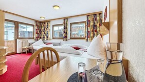 Ett hotellrum med en säng, ett skrivbord, en stol, ett bord och utsikt över staden genom stora fönster.