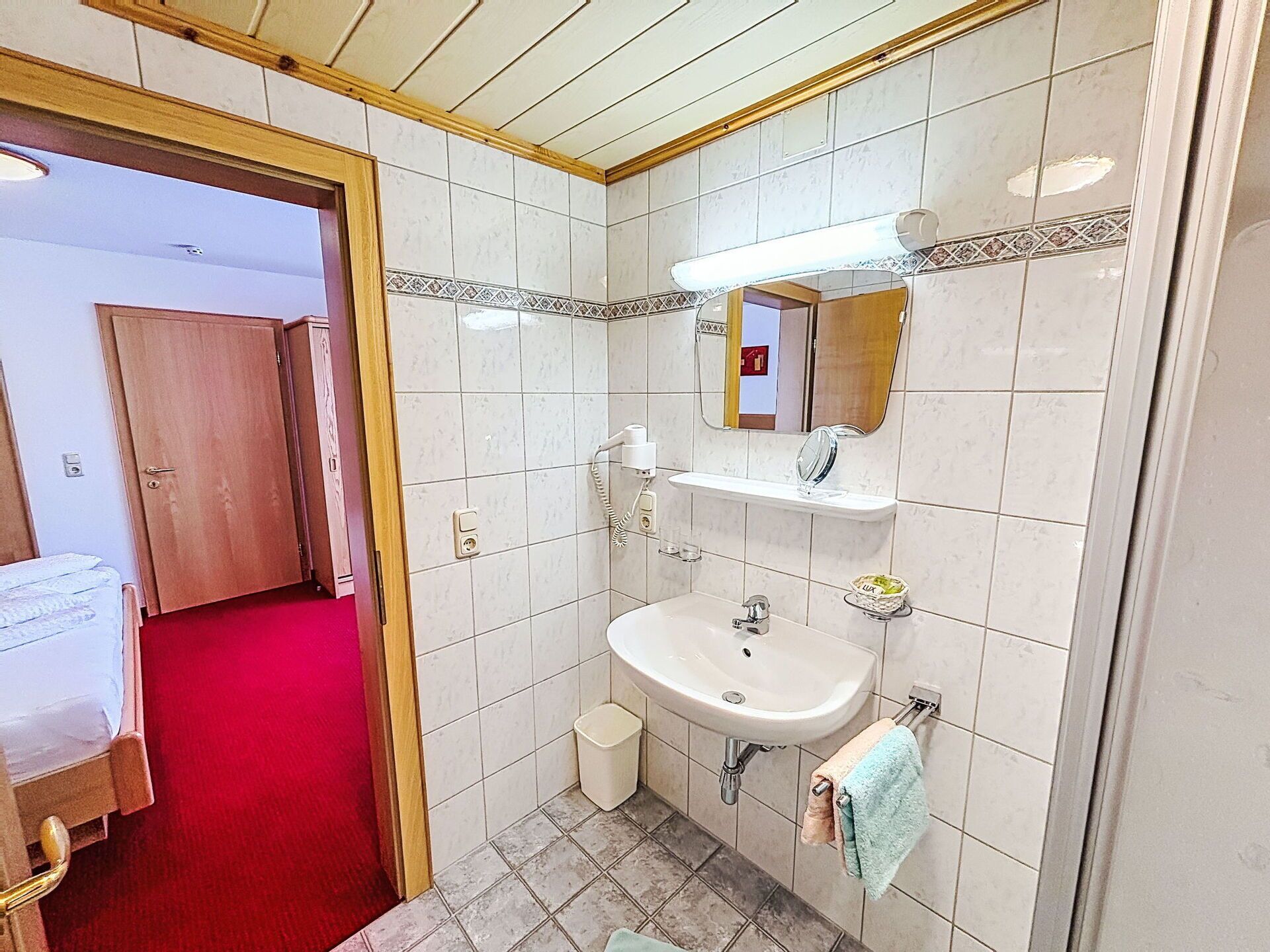 A bathroom with a sink, mirror, and towel rack.