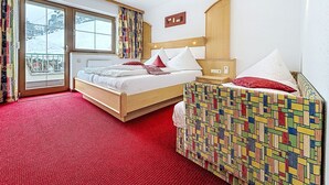 Ett hotellrum med en säng, ett litet sängbord, en stol, ett fönster med gardiner och utsikt över omgivningen.