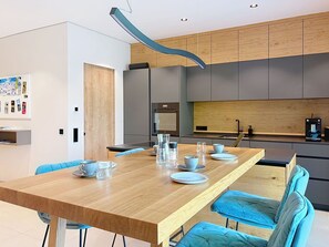 Eine moderne Küche mit einem Holztisch, blauen Stühlen und einer Kücheninsel.