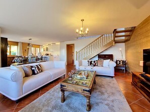 Ein geräumiger Wohnbereich mit zwei Sofas, einem Couchtisch und einer Treppe.