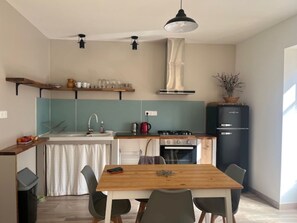 Uma cozinha compacta com área de refeições, forno embutido e luminária pendente.