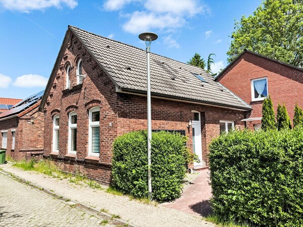 A red brick building with a sloped roof, a visible door, and a pathway leading to it. - Wonderful  villa for 6 people with WIFI, TV, terrace and pets allowed (Norden)