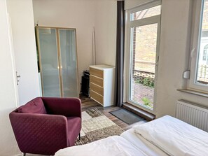 A bedroom with a bed, a chair, a wardrobe, a radiator, and a view of the outside. - Wonderful  villa for 6 people with WIFI, TV, terrace and pets allowed (Norden)