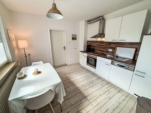 Eine moderne Küche mit weißen Schränken, einer Holz Arbeitsplatte, einem eingebauten Backofen und einem Grill.