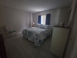 Ein Schlafzimmer mit einem Bett, einem Sessel, einer Lampe und einem Schrank.