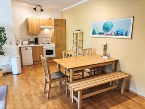 Una cocina compacta con armarios de madera, una mesa de comedor con sillas, un banco y una planta en maceta.