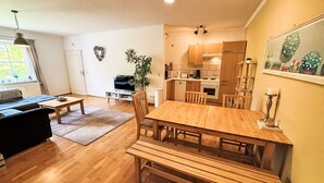 Ein moderner Wohnraum mit Essbereich, Küche und Fernseher im Wohnzimmer.