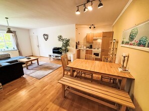 Ein moderner Wohnraum mit Essbereich, Küche und Fernseher im Wohnzimmer.