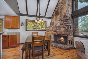 A dining area with a stone fireplace, wooden furniture, and a view of the outdoors. - Escape to St Moritz in the heart of Gatlinburg, where adventure meets comfort in (Gatlinburg)