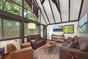 A spacious living room with large windows, a fireplace, and a cozy seating area. - Escape to St Moritz in the heart of Gatlinburg, where adventure meets comfort in (Gatlinburg)