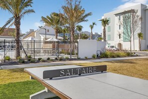 A sign with the name 'SALTAIRE' in a resort setting with palm trees and a pool area. - Landing Furnished Apartments near THSP (Santa Rosa Beach)