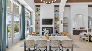 Amplia sala de estar con chimenea, televisor y comedor con sillas.