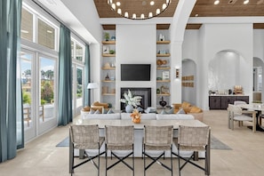 A spacious living room with a fireplace, a TV, and a dining area with chairs. - Landing Beautiful 1BD (Santa Rosa Beach)