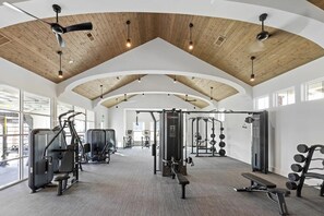 A gym with ceiling fans, exercise equipment, and large windows. - Landing Beautiful 1BD (Santa Rosa Beach)