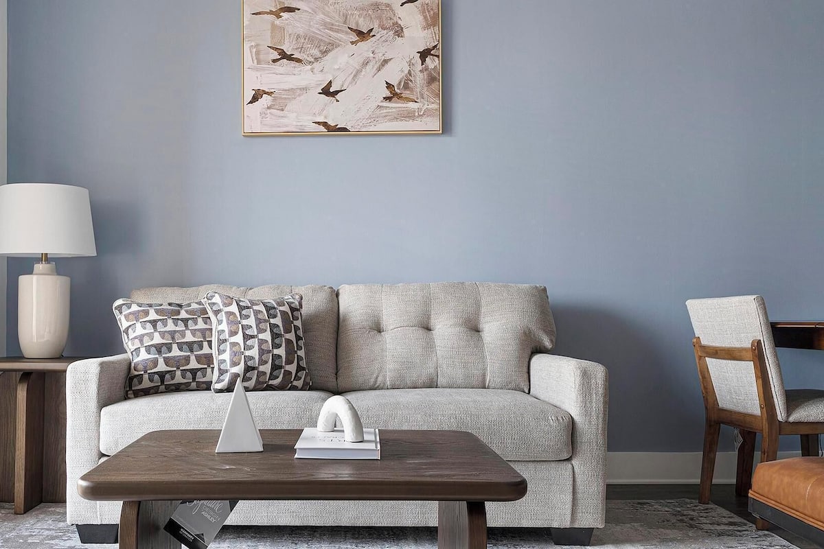 A living room with a sofa, a coffee table, a lamp, and a chair.