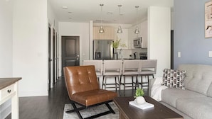 A modern living room with a brown leather chair, a grey sofa, and a wooden coffee table with a plant.
