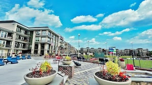 A rooftop terrace with outdoor seating and planters, overlooking a cityscape with modern buildings.