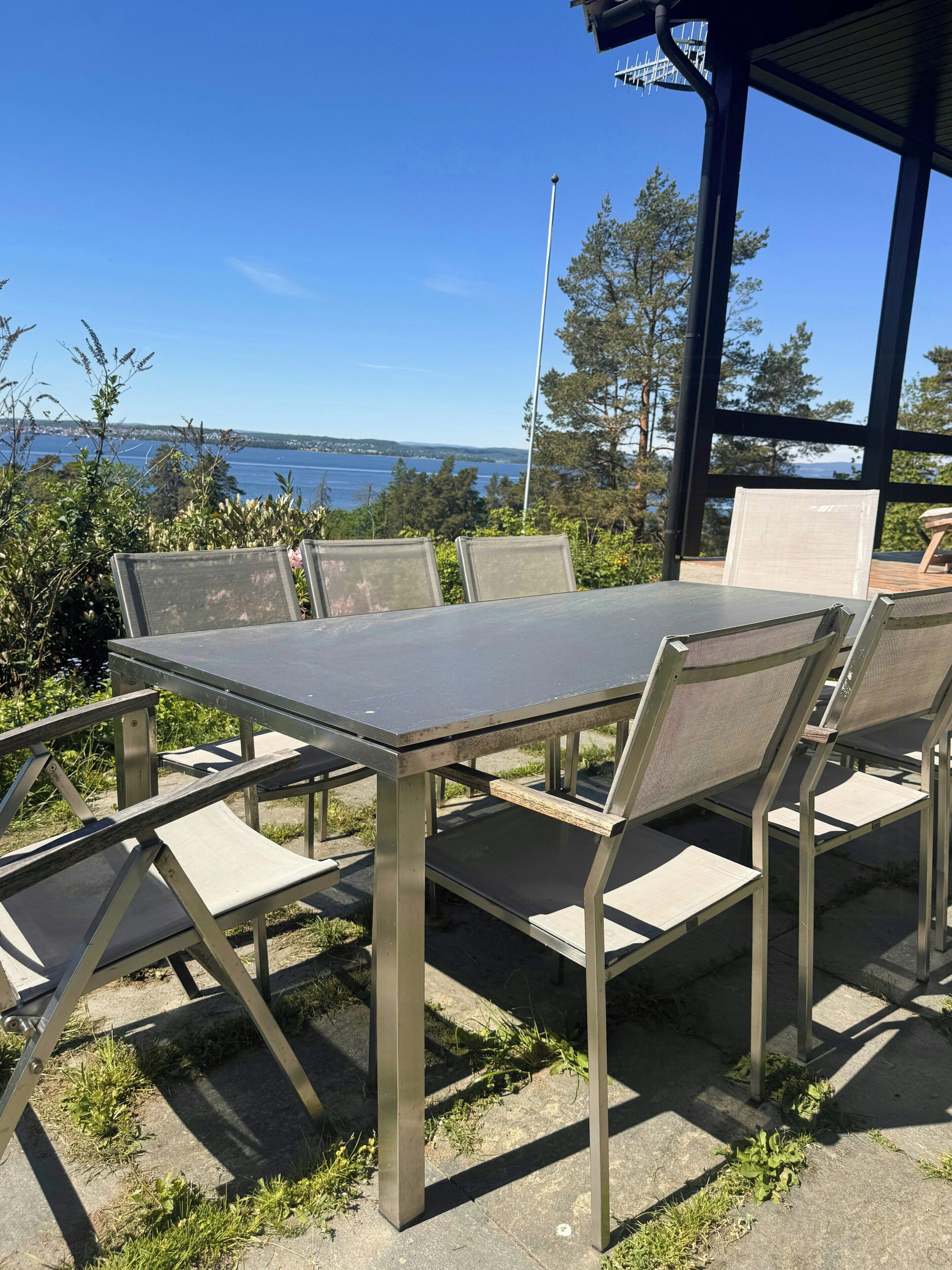 Un espace extérieur aménagé avec une table et des chaises, donnant sur une étendue d’eau.
