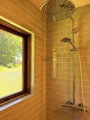 A shower with a rain showerhead, a handheld showerhead, and a handheld showerhead with a spray nozzle. - Cottage in Jeløy nature reserve with fjord view (Moss)