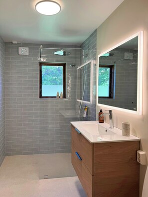 A modern bathroom with a shower, a sink, a mirror, and a window. - Cottage in Jeløy nature reserve with fjord view (Moss)